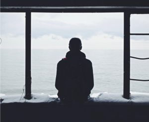 Silhouette of a man looking out of a window at a grey sky